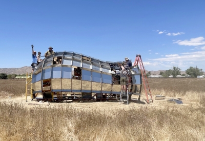 A group of people in building peepSHOW with blue skies in the desert in New Cuyama, California.