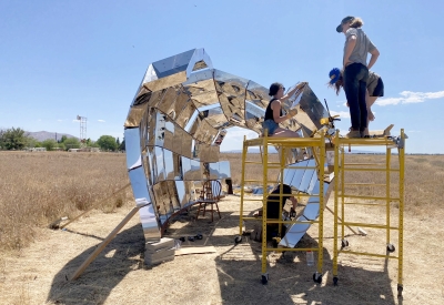 A group of people in building peepSHOW with blue skies in the desert in New Cuyama, California.