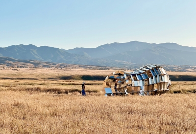 Someone walking through peepSHOW in the desert with mountains behind it in New Cuyama, California.