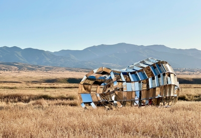 Someone walking through peepSHOW in the desert with mountains behind it in New Cuyama, California.