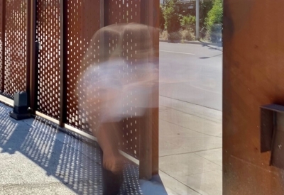 Blurred person walking through the cor-ten gate of David Baker Architects Office in Oakland, California.