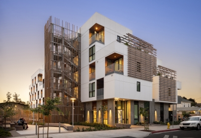 Exterior view of Page Street Studios at dusk with resident windows illuminated in San Jose, California. 