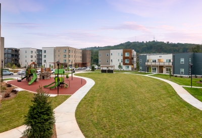 Exterior view Maple Crest Apartments surrounding a park and children's play area at at Lee Walker Heights in Asheville, North Carolina.