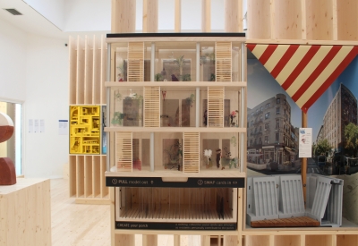 Model on display in a plywood pavilion.