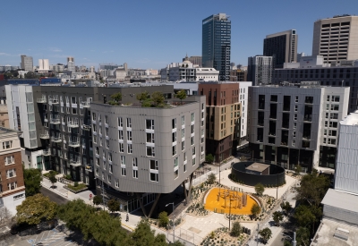 Aerial view of diverse buildings centered around a landscaped urban park with blue sky in background.