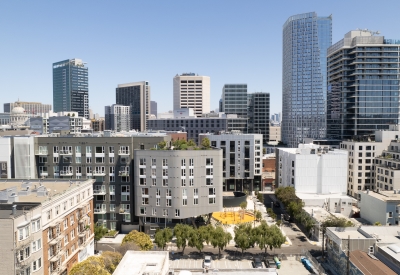 Aerial view of diverse buildings centered around a landscaped urban park with blue sky in background.