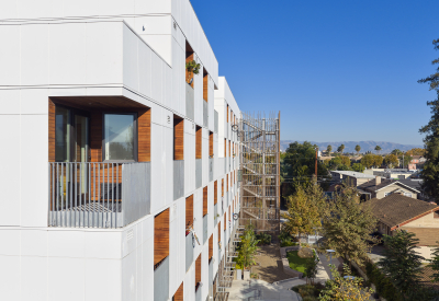 Close up corner view of balconies in checkerboard pattern in white apartment building against blue sky