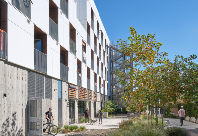 Courtyard of white apartment building with man exiting building with a bicycle