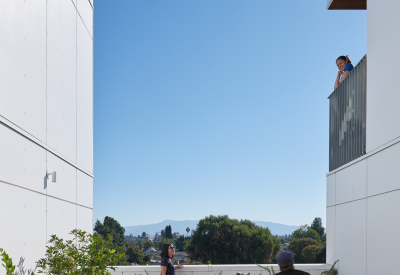 Patio view of two people with a dog talking to a woman on a balcony above
