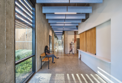 Interior view of apartment building lobby with bench, reception desk enclosed with wood doors, and elevator