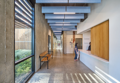 Interior view of apartment building lobby with bench, open reception desk, and elevator