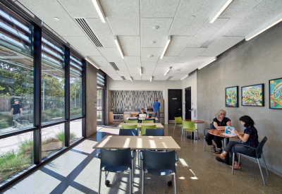 Interior of community room with glass wall at left and people sitting and reading