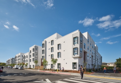 Large white building viewed from corner crosswalk against bright blue sky