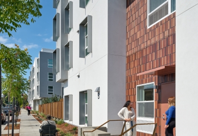 Stoop connecting to sidewalk, with two women talking and a man in a scooter on the sidewalk