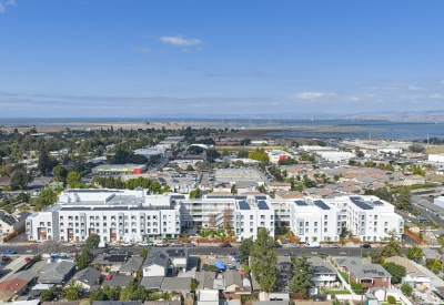 Straight-on aerial view of large white building set in an urban context