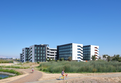 Large gray and white building against blue sky with bike path in the foreground