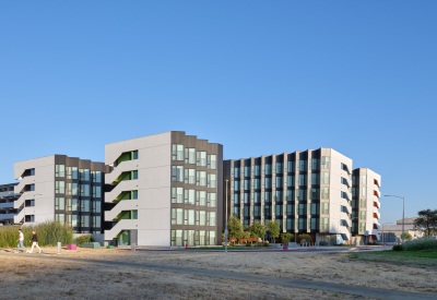 Large gray and white building against blue sky with bike path in foreground 