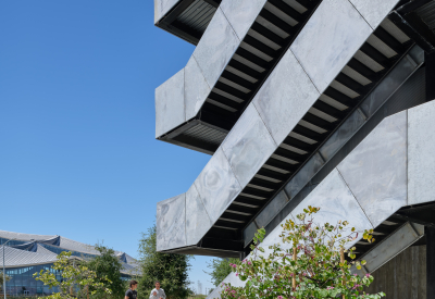 Gray exterior stair against blue sky with bikes parked in front 