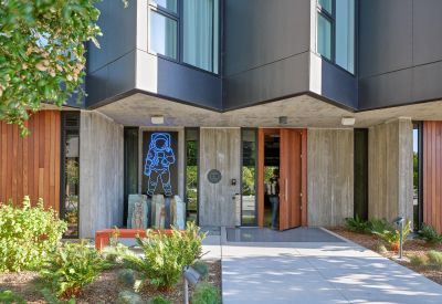 Gray building with man walking through brown wood door