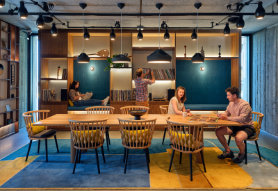 Room with blue and yellow rug and two people sitting at large rectangular table