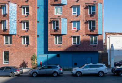 Front view of apartment facade showing terra-cotta brick and blue brick