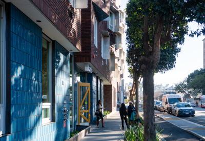 Yellow entry door of apartment building on tree-lined street