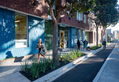Street view of apartment entry with pedestrians and cyclist