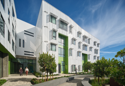 Exterior of white apartment building with green entry portals