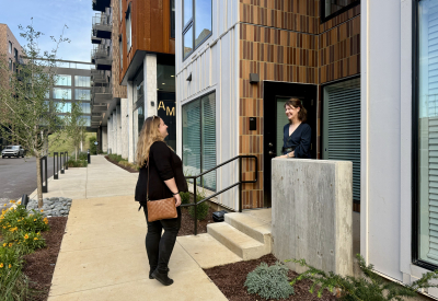 Two people talking on stoop of building with crosswalk in background 