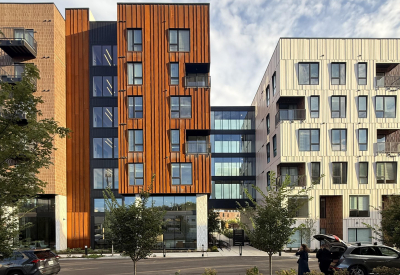 Mid rise building with patinated corten steel across a street