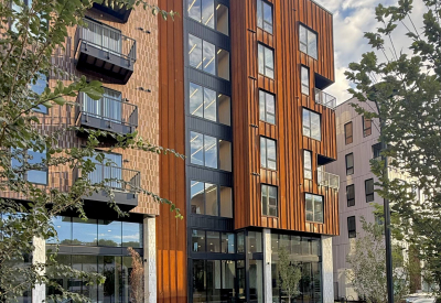 Rust colored corner building with trees and car in the foreground