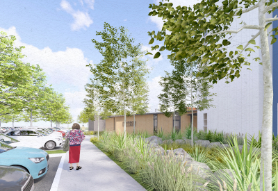 Woman walking on sidewalk with white building on the right 