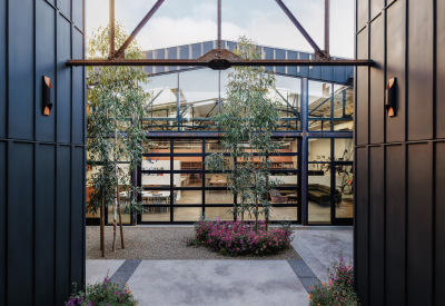 Space between two dark buildings with gravel path and view of glass and steel building 