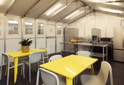 Interior of prefab kitchen structure with bright yellow tables