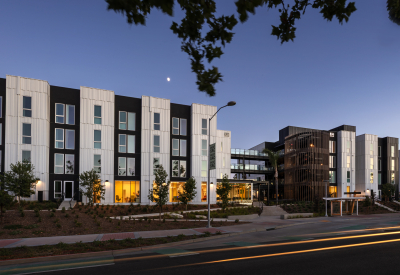 Elevation of multifamily building with black and white vertical bays taken just past dusk