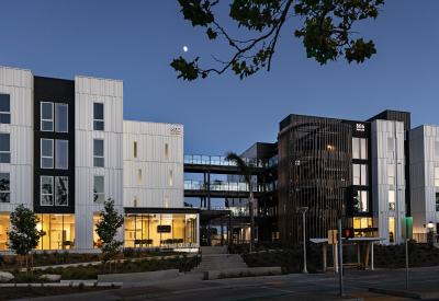 Distant view of entry plaza of multfamily building with black and white bays taken just past dusk