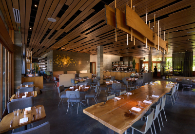 Interior of a restaurant at dusk with custom wood ceiling, lighting, and host stand