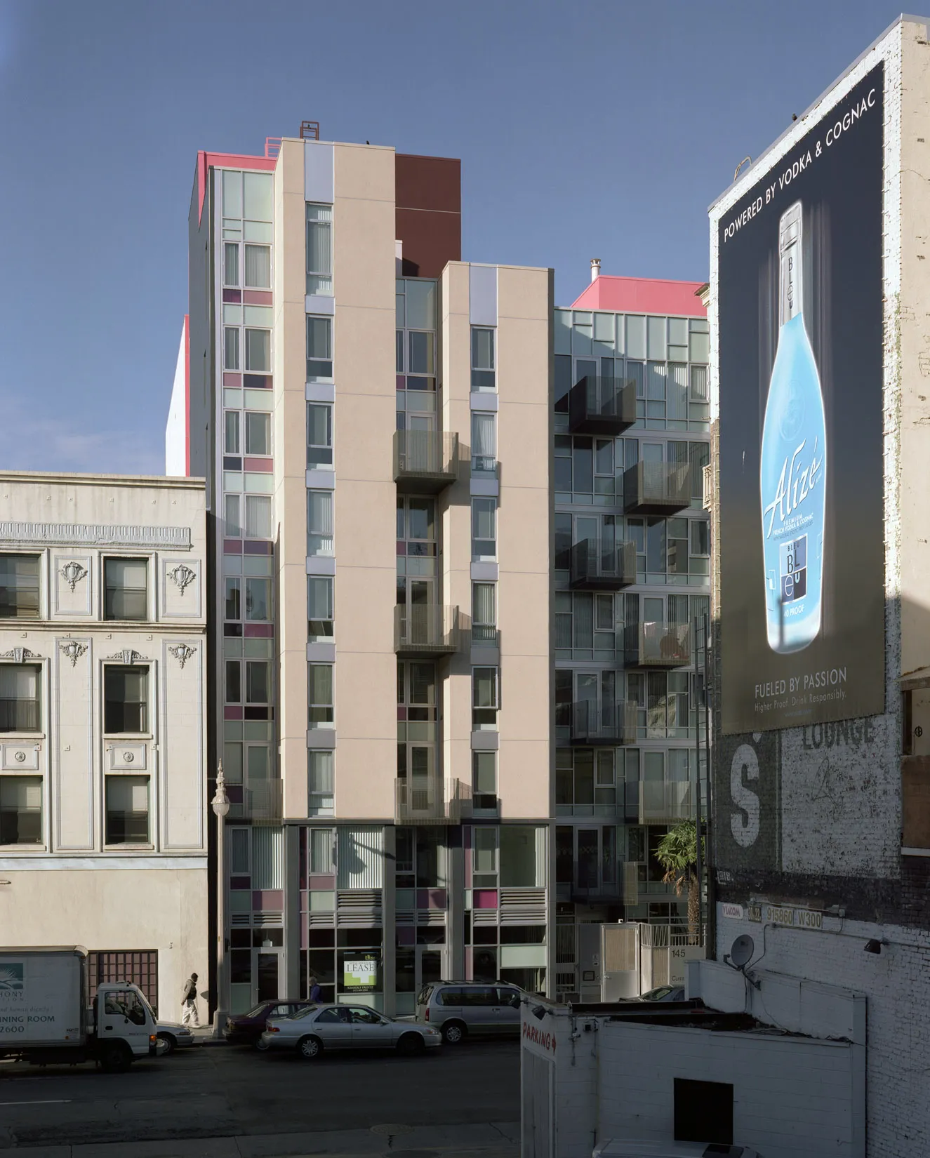 Elevation view of Curran House showing balconies and bright pink accents, with billboards in the foreground.