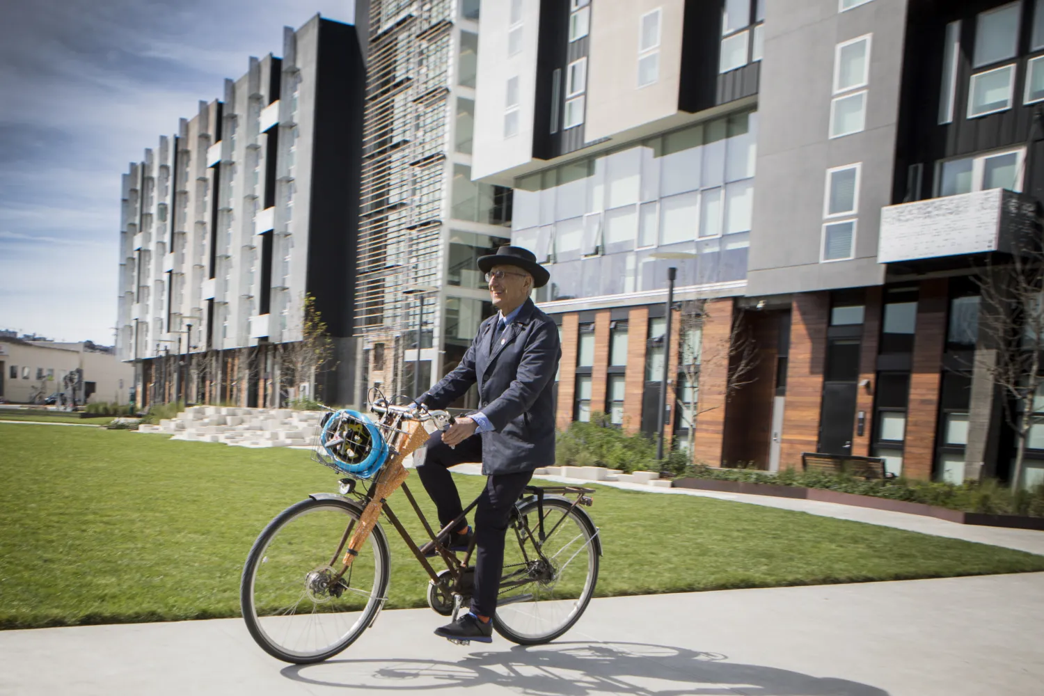 David Baker riding an orange bike on a path in Daggett Plaza at Potero 1010 in San Francisco.