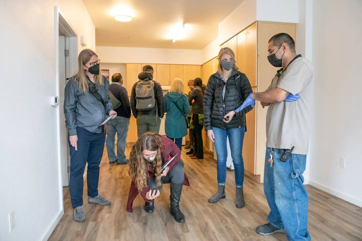 A group of nine people in a building unit, one person crouching down and taking a photo. 