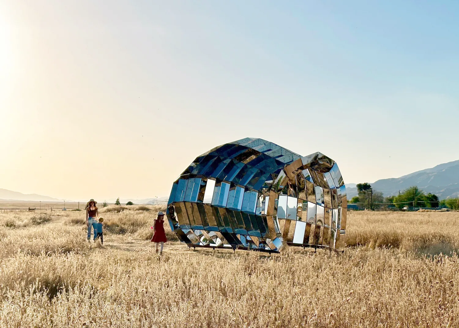 A woman and two children stand by peepshow in the desert with mountains in the background at New Cuyama, California.