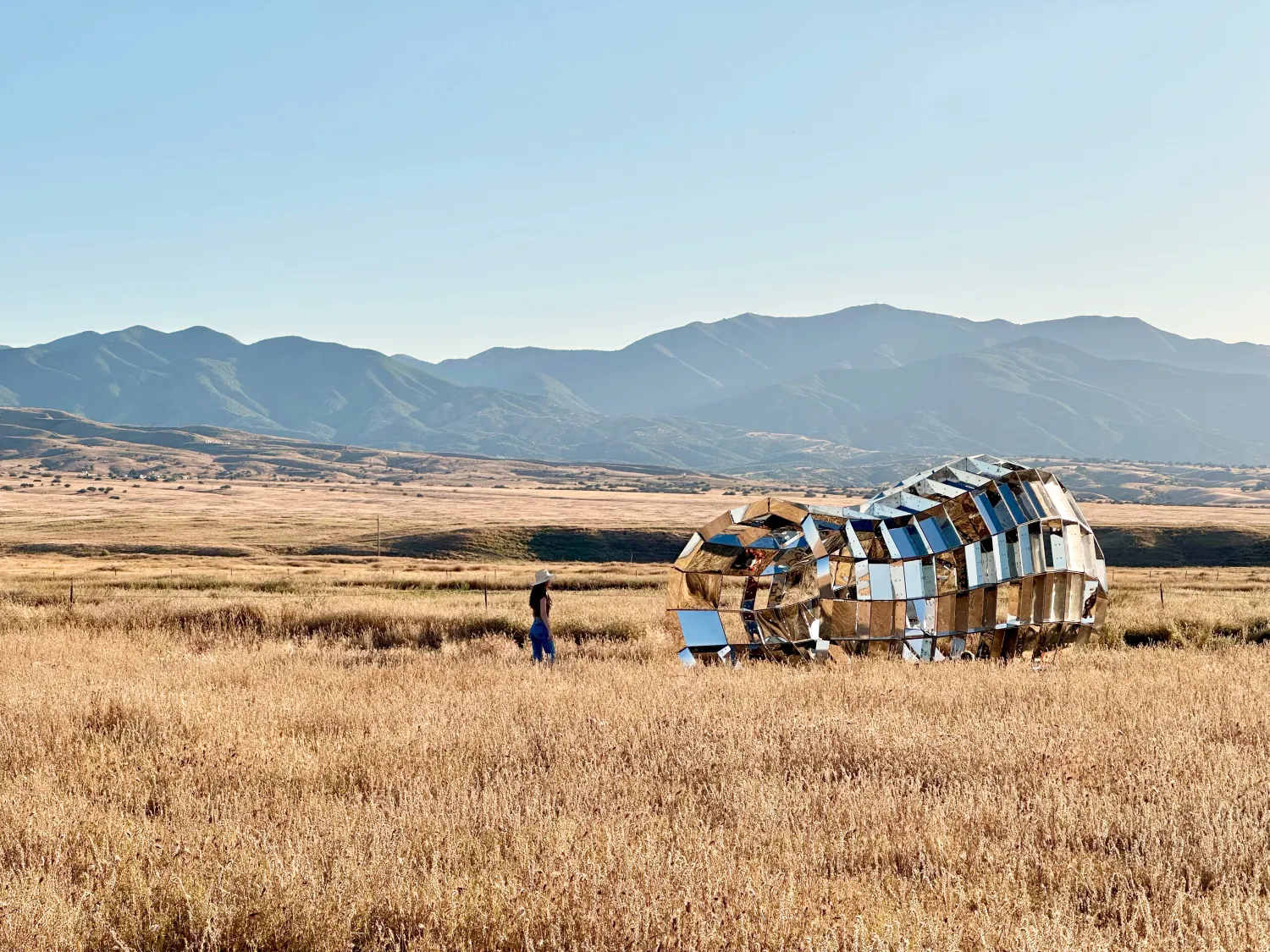 Someone walking through peepSHOW in the desert with mountains behind it in New Cuyama, California.