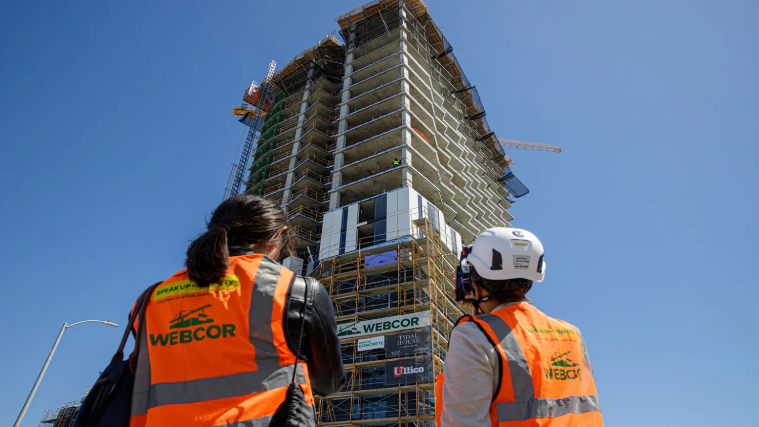 Two people in construction gear looking up to Tidal House SF under construction.