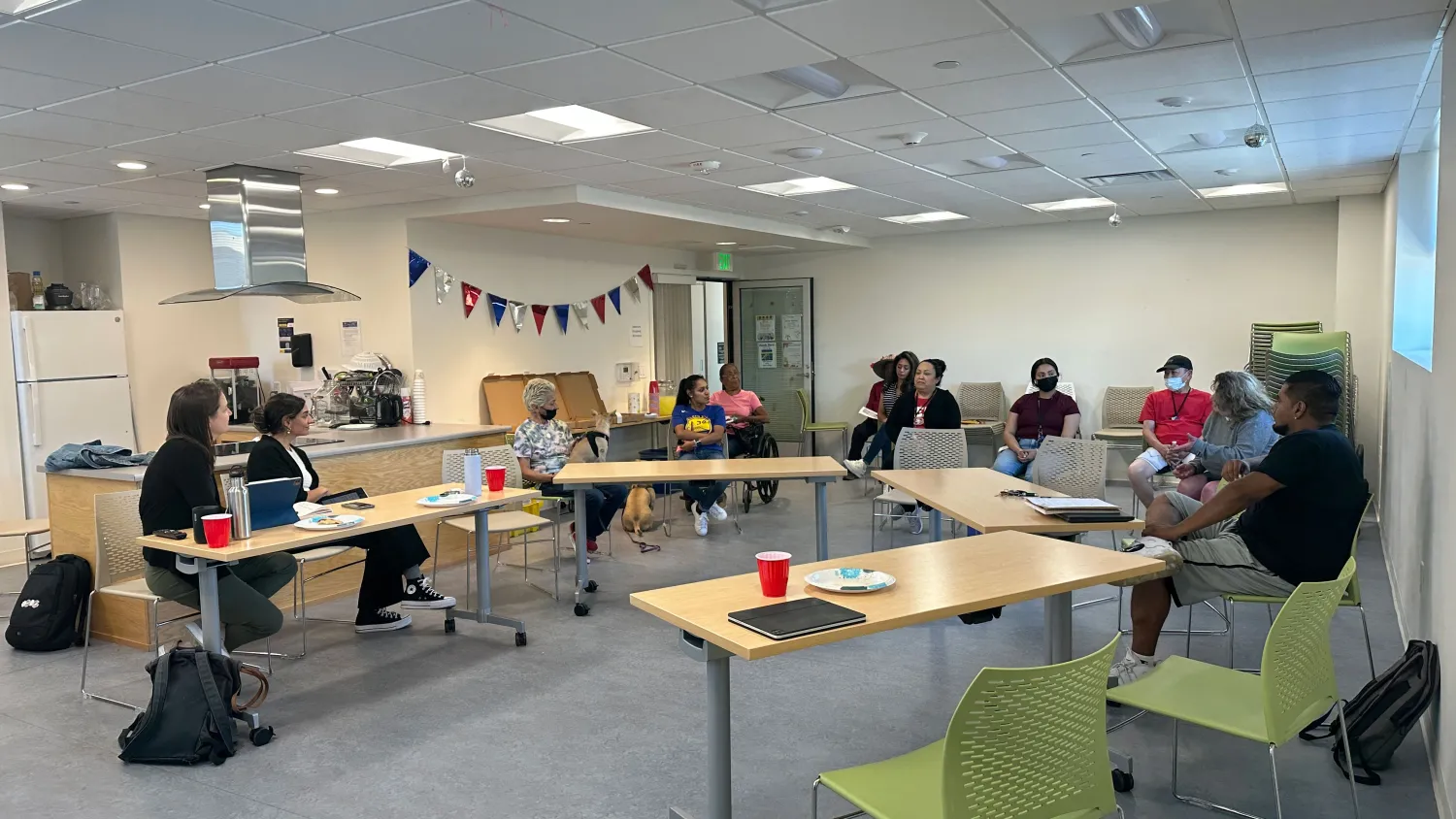 People sitting in a circle during a meeting for resident feedback.