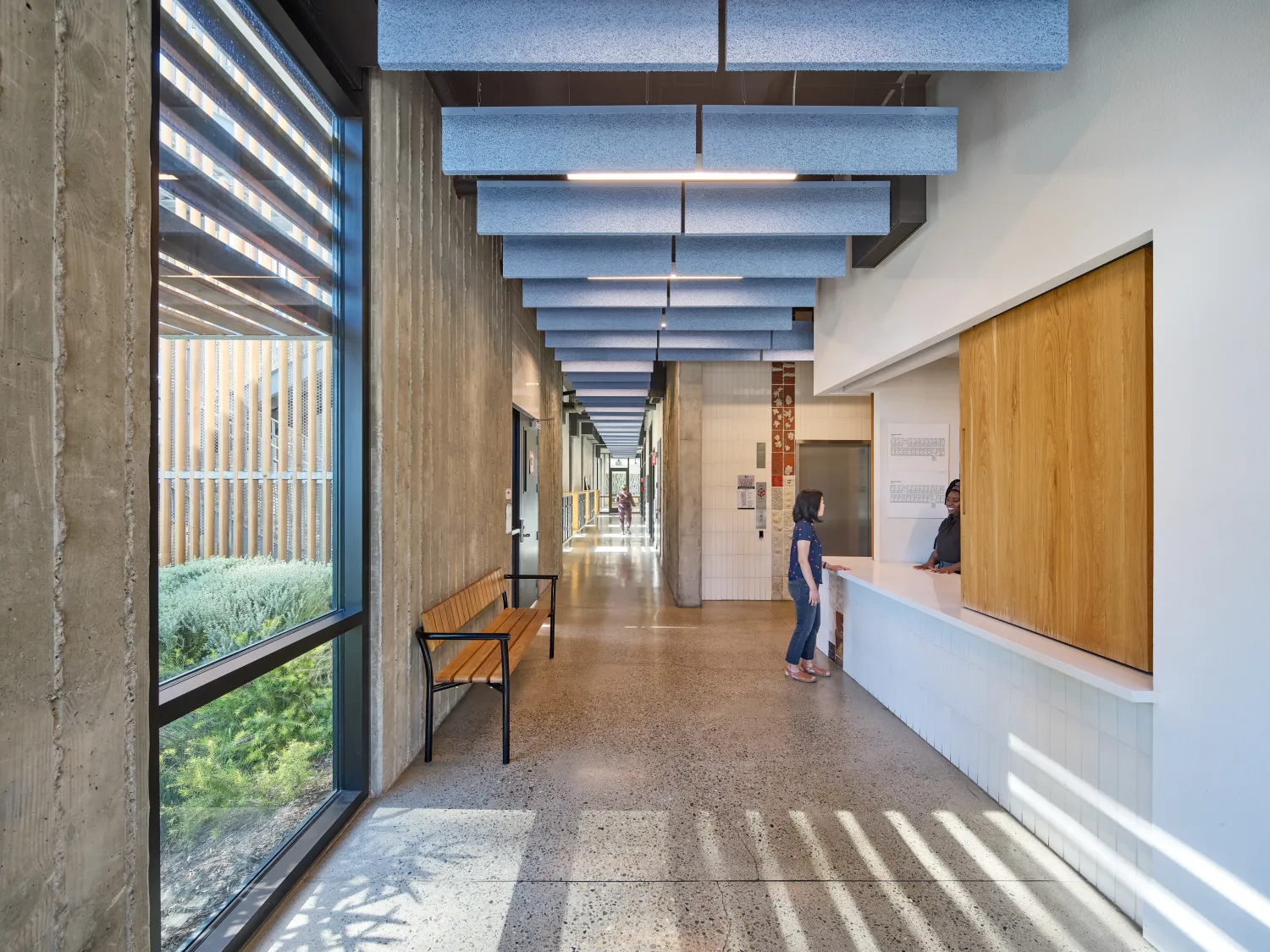 Interior view of apartment building lobby with bench, open reception desk, and elevator