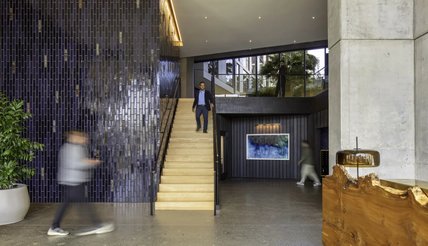 Interior view of apartment lobby with ceramic wall, stair, and people