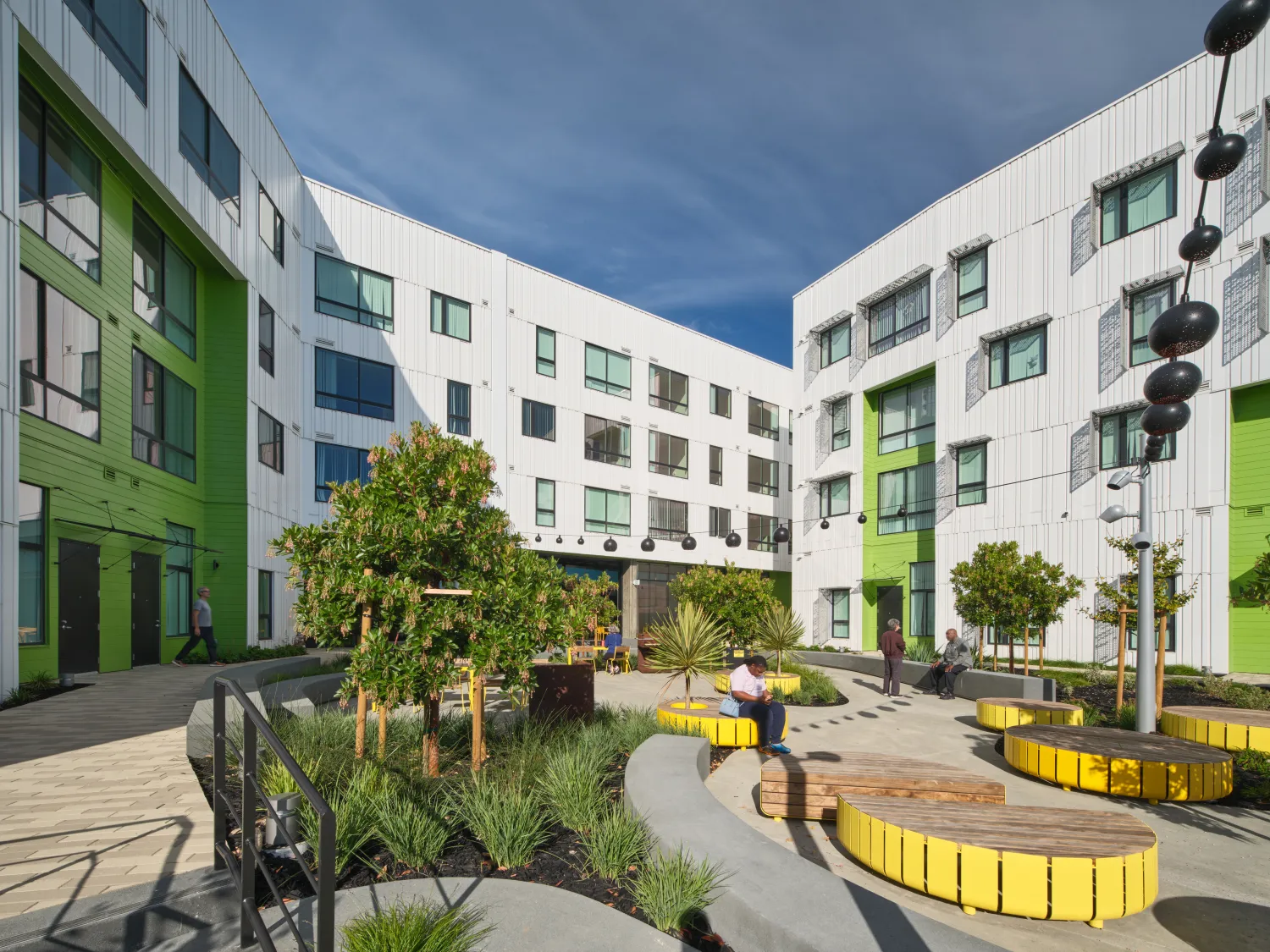 Open courtyard between apartment buildings with vegetation and people