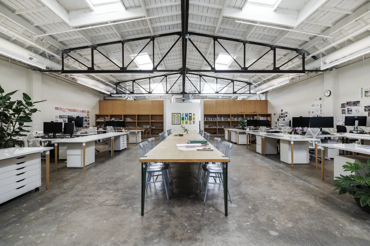 White interior space with black truss and long table down the center of the room