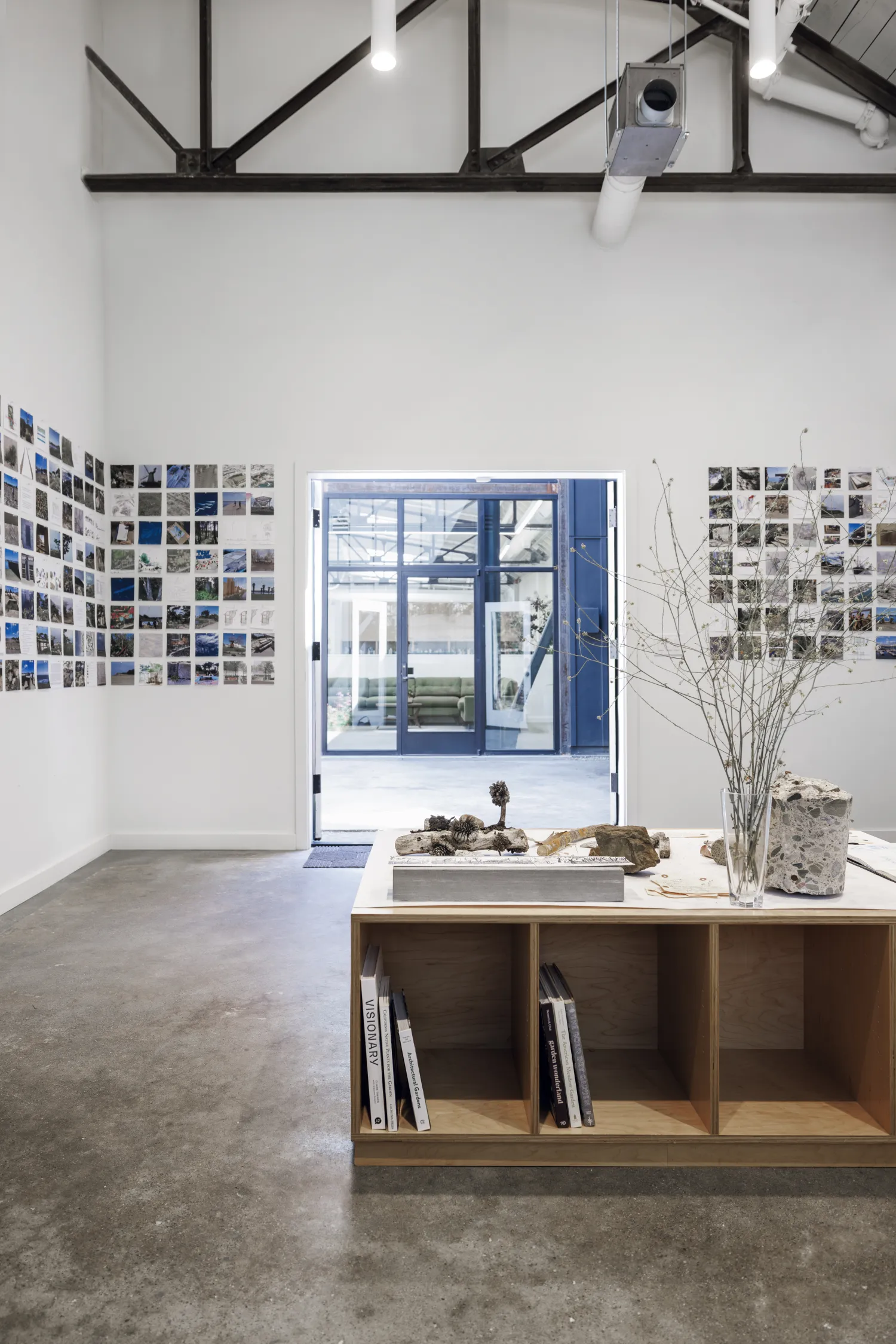 White office space with images on the walls, black truss, and brown wooden desk 