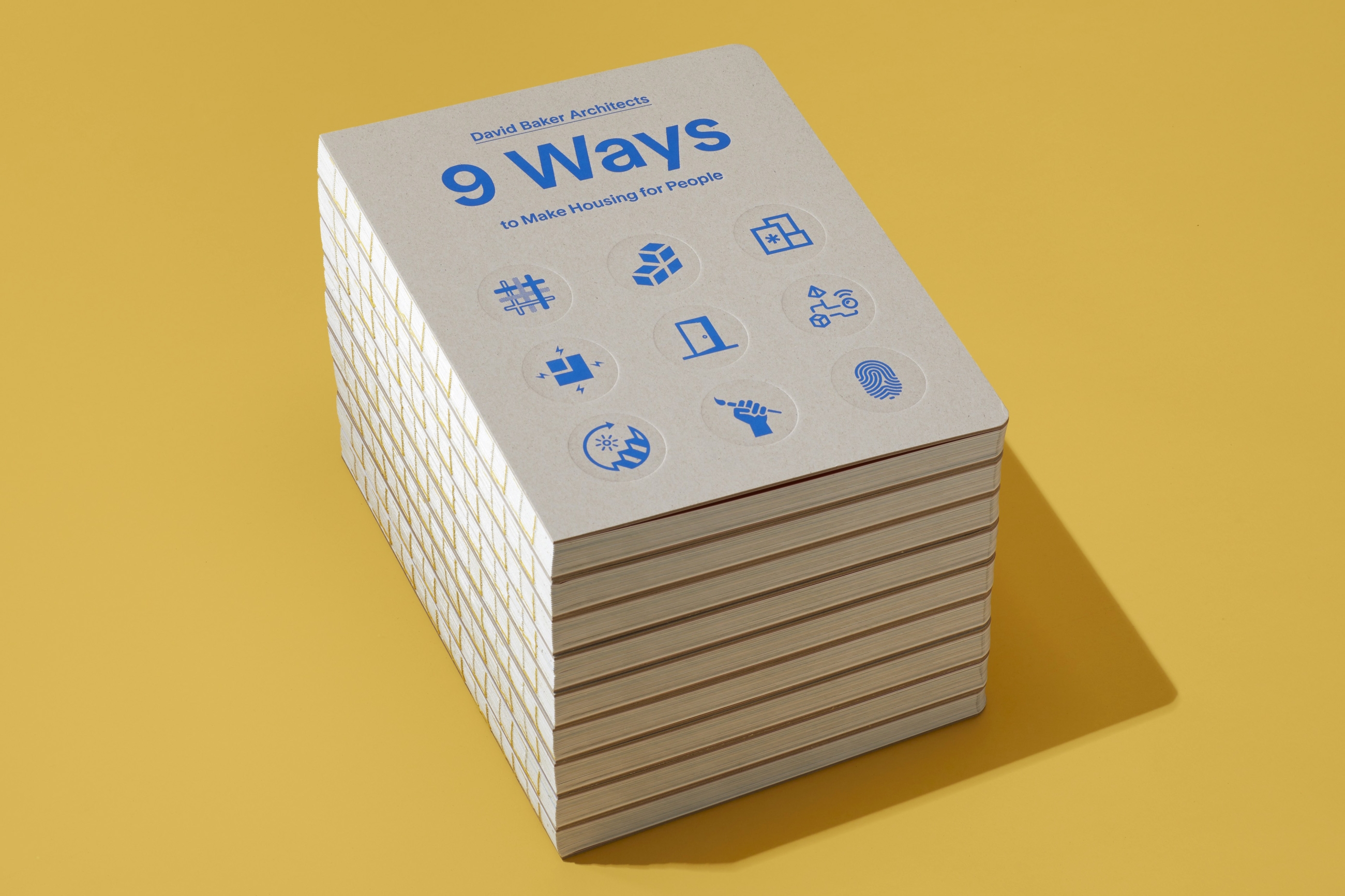 Stack of DBA’s new book 9 Ways to Make Housing for People on a bright yellow background.
